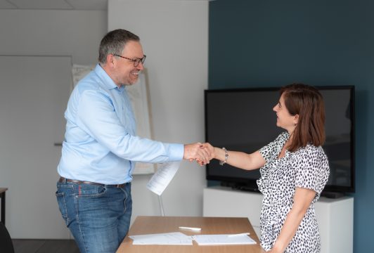 Un conseiller en formation linguistique serre la main d'une cliente.